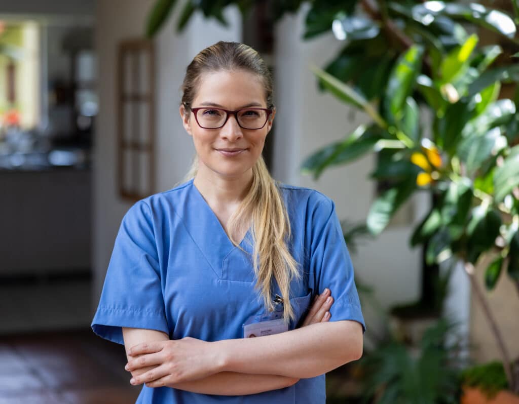 Portrait of a female home caregiver working at the house of a patient and looking at the camera - assisted living concepts