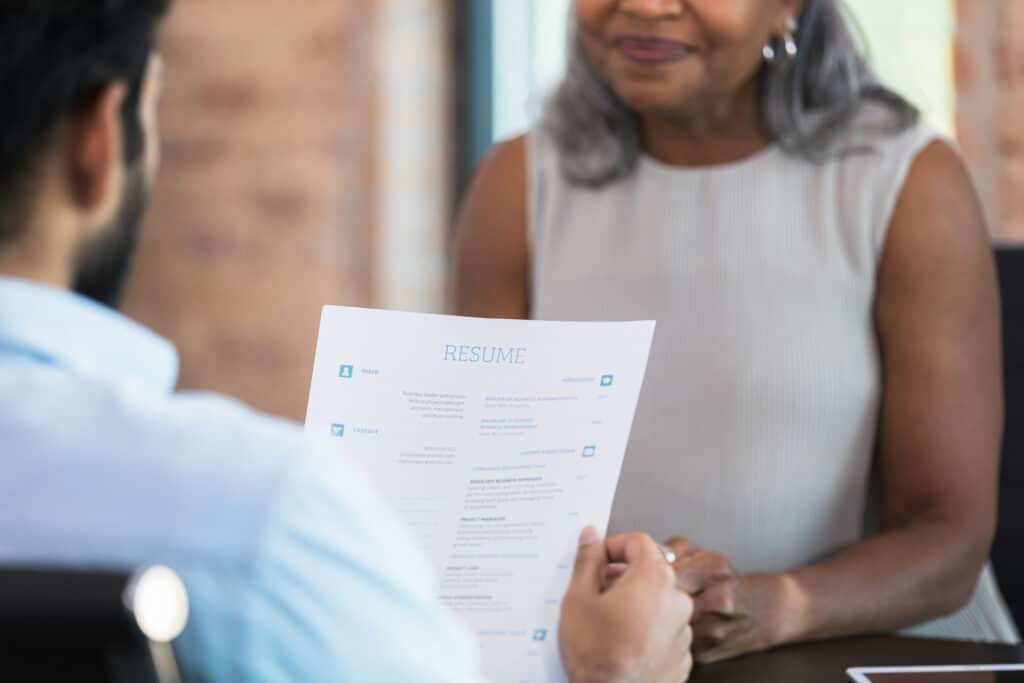 A businessman reads a resume during a job interview with a potential employee.